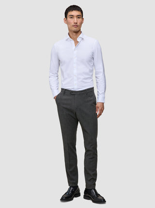 Ein Mann, der ein weißes Hemd, eine Motion Suit-Hose in der Farbe Slim Pepper Grey und schwarze Slipper trägt.