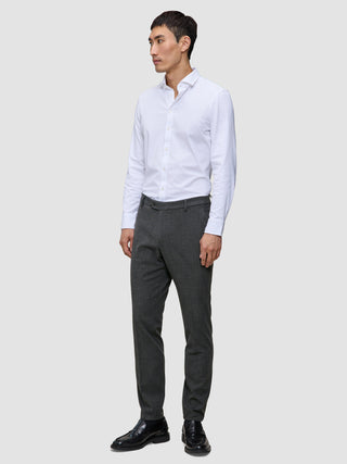 Ein Mann, der ein weißes Hemd, eine Motion Suit-Hose in der Farbe Slim Pepper Grey und schwarze Anzugschuhe trägt.