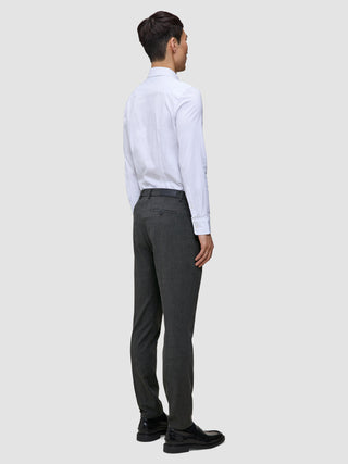 Ein Mann, von hinten gesehen, der ein weißes Hemd, eine Motion Suit-Hose in der Farbe Slim Pepper Grey und schwarze Slipper trägt.