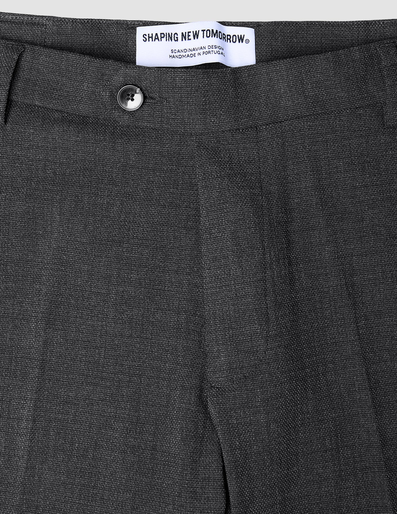 Nahaufnahme der Motion Suit-Hose Slim Pepper Grey in Dunkelgrau, mit schmaler Passform, Knopfverschluss und Markenetikett am Bund.