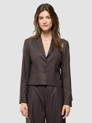 Eine Frau, die einen kurzen Damenblazer „Raina“ in der Farbe „Chestnut“ mit Nadelstreifen trägt und dabei einen eleganten Eindruck macht.