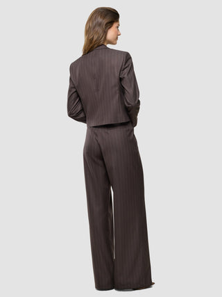 Eine Frau, von hinten gesehen, trägt den „Women Raina Short Blazer“ in der Farbe „Chestnut Pinstripe“ sowie eine dazu passende Hose mit weitem Bein, was einen eleganten Look ergibt.