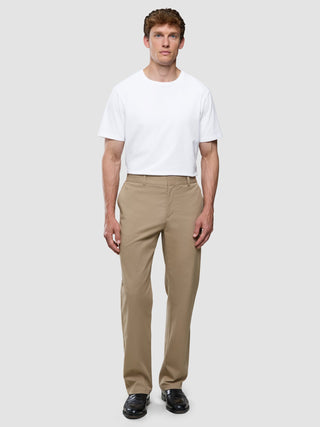 Ein Mann, der ein weißes T-Shirt und eine „Refine Cotton Pants Relaxed Fit Sand“ trägt.