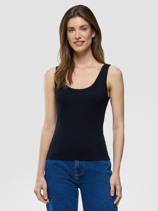 Eine Frau, die ein schwarzes Rib-Tanktop und eine blaue Jeans trägt.