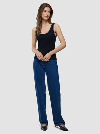 Eine Frau, die ein schwarzes Ripp-Tanktop und eine blaue Jeans trägt.