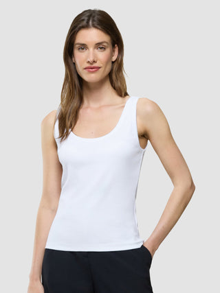 Eine Frau, die ein weißes Ripp-Tanktop und eine schwarze Hose trägt.
