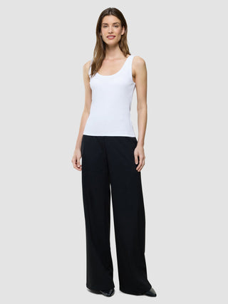 Eine Frau, die ein weißes Rib-Tanktop und eine schwarz-weiße Hose mit weitem Bein trägt.