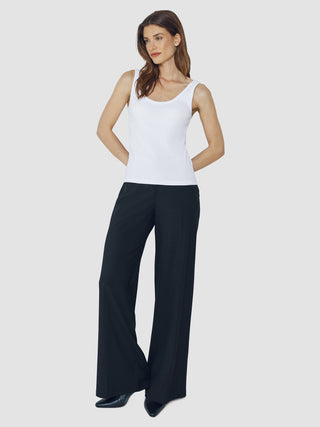 Eine Frau, die ein weißes Tanktop mit Rippenmuster und eine schwarze Hose mit weitem Bein trägt.