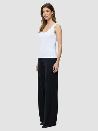 Eine Frau, die ein weißes Rib-Tanktop und eine schwarz-weiße Hose mit weitem Bein im skandinavisch inspirierten Stil trägt.