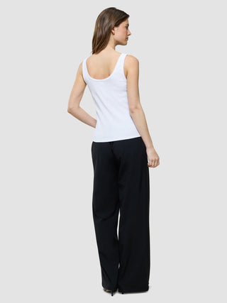 Eine Frau, von hinten gesehen, die ein weißes Rib-Tanktop und eine schwarz-weiße Hose mit weitem Bein im minimalistischen, skandinavischen Design trägt.