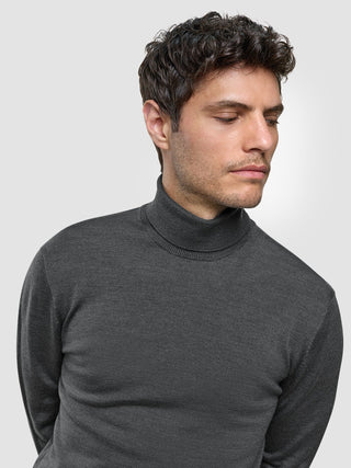 Ein Mann, der einen nahtlosen Premium-Merino-Strickpullover mit Rollkragen in Anthrazit trägt.