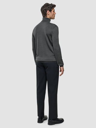 Ein Mann, der einen nahtlosen Premium-Merino-Strick-Rollkragenpullover in Anthrazit und eine dunkle Hose trägt, von hinten gesehen.