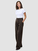Eine Frau, die ein weißes T-Shirt und die Serene Pants Wide Walnut Herringbone trägt, die sich durch ein dezentes vertikales Streifenmuster und einen weiten Schnitt im skandinavischen Stil auszeichnen.