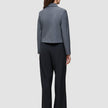 Eine Frau, von hinten gesehen, die einen grauen Blazer und eine schwarze Serene Pants Wide Black mit weitem Bein trägt.
