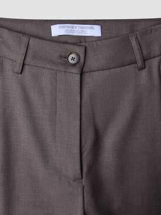 Nahaufnahme der Damenhose „Skye“ in schmal zulaufender Passform, dunkelkastanienbraun meliert, mit einem Etikett mit der Aufschrift „Shaping New Tomorrow“, skandinavisches Design, handgefertigt in Portugal.
