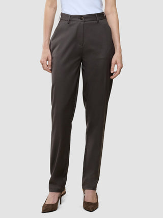 Eine Person, die eine „Women Skye Pants Tapered Dark Chestnut Melange“ trägt, dazu ein weißes Oberteil und braune Pumps.
