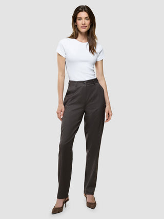 Eine Frau, die in einem weißen T-Shirt, einer „Women Skye Pants Tapered Dark Chestnut Melange“ und Pumps mit spitzer Zehenpartie posiert – gestylt im minimalistischen skandinavischen Design.