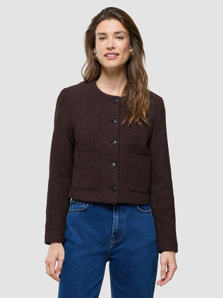 Eine Frau, die eine „Women Sorae Short Jacket“ in der Farbe „Espresso“ und eine blaue Jeans trägt.