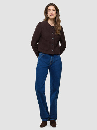 Eine Frau, die die Damen-Kurzjacke „Sorae“ in der Farbe „Espresso“ und eine blaue Jeans trägt.