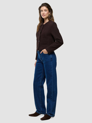 Eine Frau, die eine „Women Sorae Short Jacket Espresso“ trägt, kombiniert mit einer blauen Jeans.