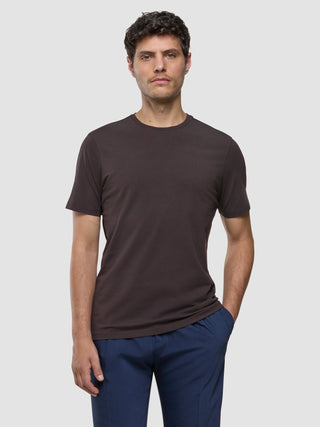 Ein Mann, der ein Supima-T-Shirt in Deep Brown und eine blaue Hose mit 360°-Stretch trägt.