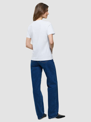 Eine Frau, die ein weißes Supima-T-Shirt und eine blaue Jeans trägt, von hinten gesehen.