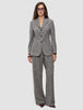 Eine Frau trägt einen grauen, strukturierten Women Ashryn Pants Wide Domino Herringbone-Anzug aus Bouclé-Stoff mit Fischgrätenmuster, bestehend aus einem Blazer mit drei Knöpfen und einer hoch taillierten Hose mit weitem Bein.