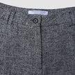 Nahaufnahme des Bunds der Damenhose Ashryn Pants Wide Domino Herringbone aus schwarz-weißem Bouclé mit einem einzelnen Knopf in der Mitte und einem weißen Markenetikett.
