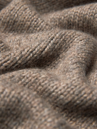 Nahaufnahme des Damen-Rollkragenpullovers aus grobem, weichem Wollstrick in Taupe-Melange, der sich durch einen taupefarbenen, grob gestrickten Stoff mit sichtbarer Rippenstruktur auszeichnet.
