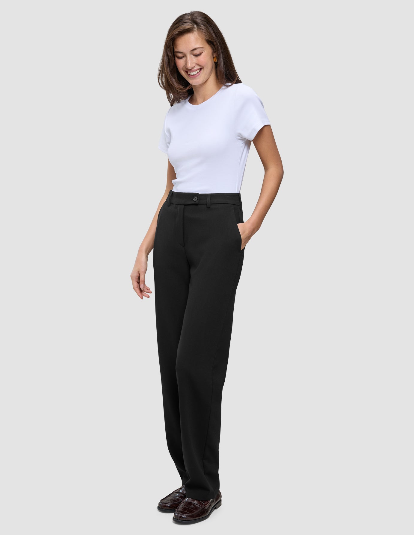 Eine Frau, die ein weißes T-Shirt und eine Women GO2 Pants Straight Black in einem schlichten, skandinavischen Design trägt.