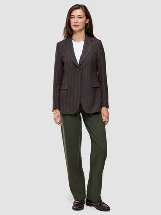 Eine Person trägt einen braunen Blazer mit Nadelstreifen über einem weißen T-Shirt, dazu die Hose Women GO2 Pants Straight Dusty Olive und dunkle Loafer – ein eleganter Look ganz im Sinne des skandinavischen Designs.