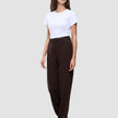 Eine Frau, die ein weißes T-Shirt, eine Women GO2 Pants Straight Mocha und dunkle Loafer trägt, die ein klares, skandinavisches Design widerspiegeln.