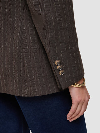 Nahaufnahme eines Women Serene-Blazers in der Passform Regular in der Farbe Walnut mit Fischgrätenmuster am Ärmel, brauner Fischgrätenstruktur in Wolloptik, drei Knöpfen an den Manschetten und einem goldenen Armreif am Handgelenk.