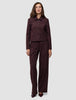 Eine Frau, die die kurze Damenjacke Serene in Berry Pinstripe und eine dazu passende Hose mit weitem Bein im minimalistischen skandinavischen Stil trägt.