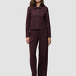 Eine Frau, die die kurze Damenjacke Serene in Berry Pinstripe und eine dazu passende Hose mit weitem Bein im minimalistischen skandinavischen Stil trägt.