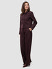 Eine Frau trägt die Women Serene Short Jacket Berry Pinstripe, eine kastenförmige, dunkelviolette Jacke mit Nadelstreifen, kombiniert mit einer passenden Hose mit hoher Taille im schlichten, skandinavischen Design.