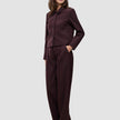 Eine Frau trägt die Women Serene Short Jacket Berry Pinstripe, eine kastenförmige, dunkelviolette Jacke mit Nadelstreifen, kombiniert mit einer passenden Hose mit hoher Taille im schlichten, skandinavischen Design.