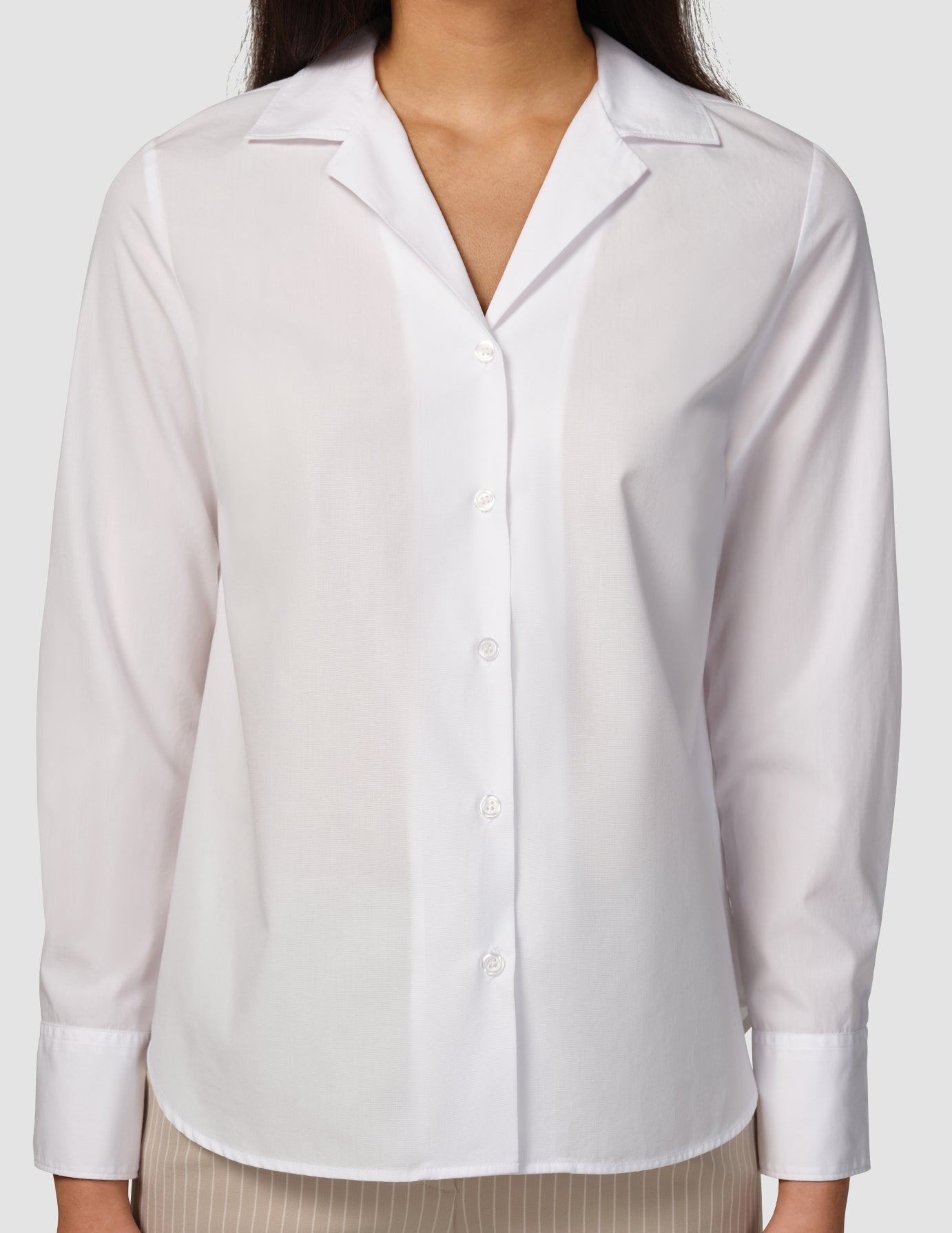 Eine Frau, die ein „Madison Shirt White“ trägt, ein langärmeliges Hemd mit Knopfleiste und gekerbtem Kragen im minimalistischen skandinavischen Design.
