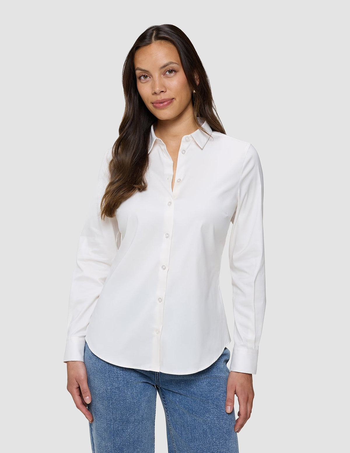 Eine Frau, die ein weißes Damen-Oxford-Hemd White Orchid Slim mit klassischem Kragen und eine blaue Jeans trägt.