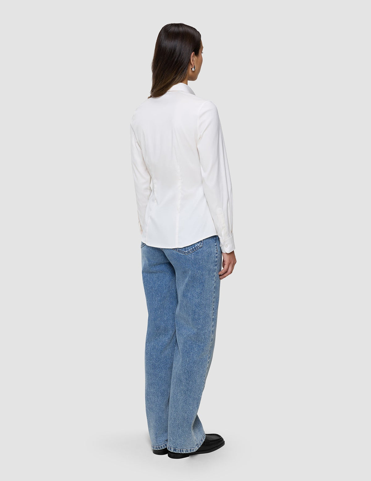 Eine Person, von hinten gesehen, die ein Damen-Oxford-Hemd White Orchid Slim und eine blaue Jeans trägt.