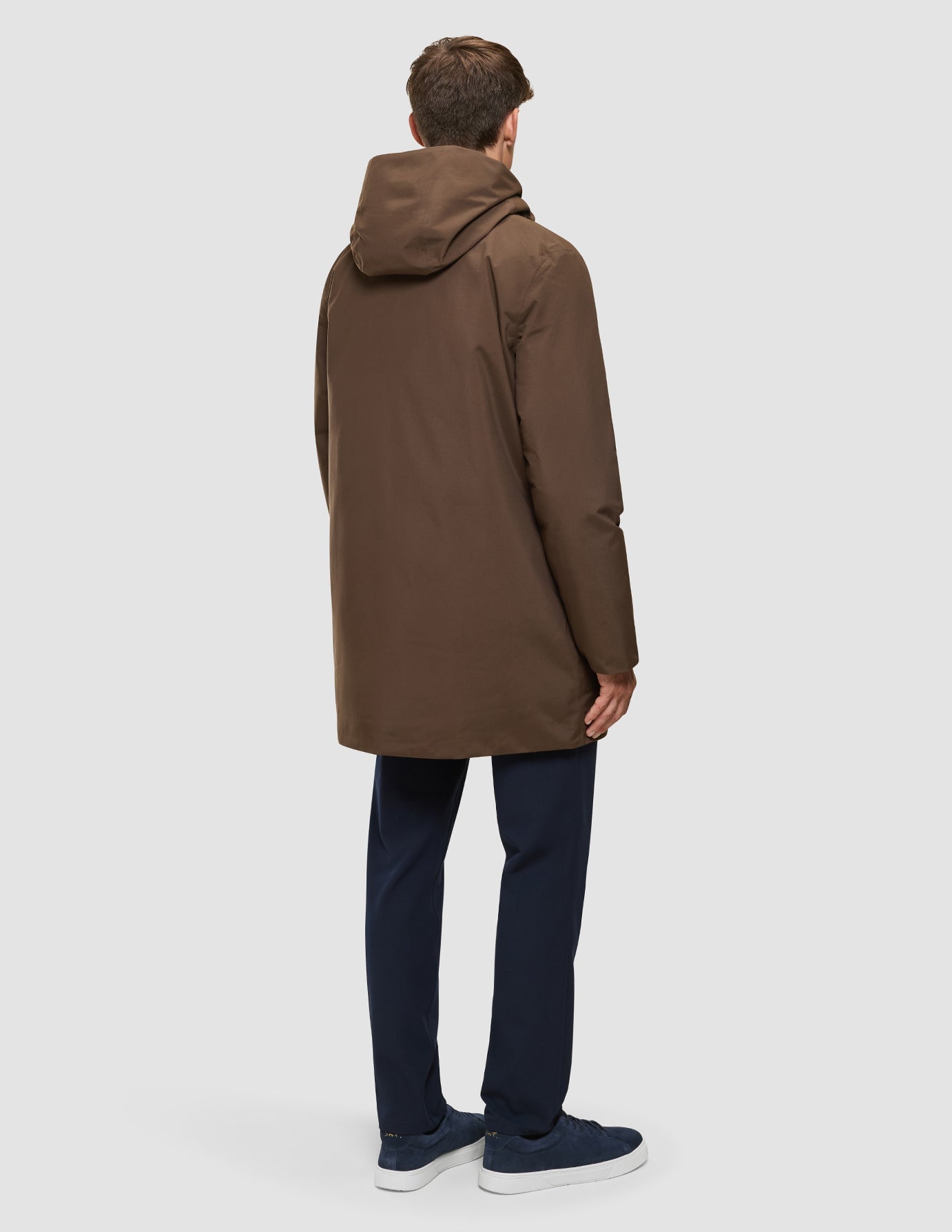 Eine Person, von hinten gesehen, die eine braune Utility-Jacke in der Farbe Saddle Brown, eine marineblaue Hose und marineblaue Sneaker trägt.
