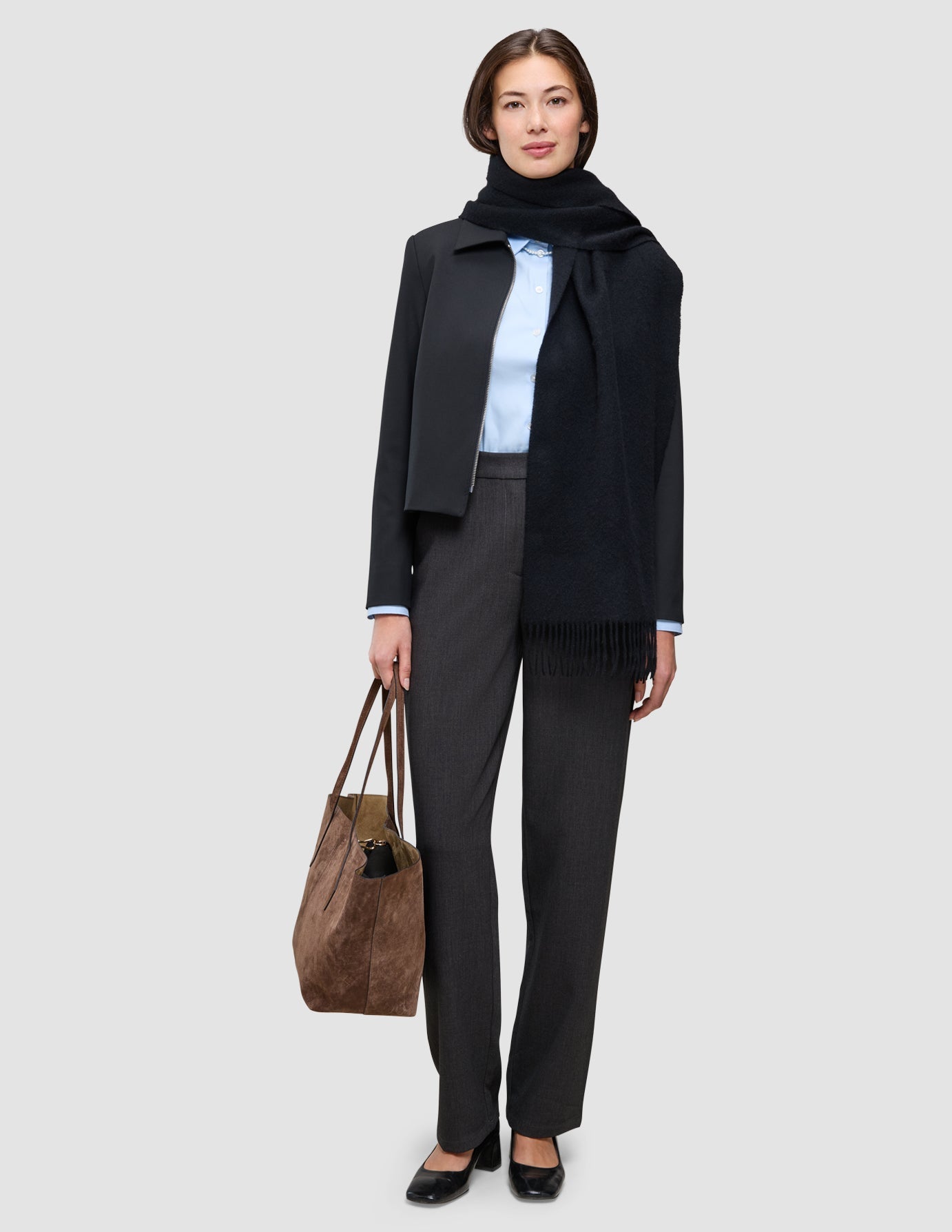 Eine Frau trägt ein An Easy Office Upgrade über einem hellblauen Oxford-Hemd, einer dunkelgrauen Hose und einem schwarzen Schal und hält dabei eine braune Tragetasche in der Hand.