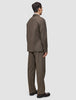 Ein Mann, von hinten gesehen, der ein Atelier Overshirt Dark Beige aus gebrochenem Twill trägt, dazu eine passende Hose und dunkle Loafer – ein Inbegriff des minimalistischen skandinavischen Designs.