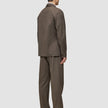 Ein Mann, von hinten gesehen, der ein Atelier Overshirt Dark Beige aus gebrochenem Twill trägt, dazu eine passende Hose und dunkle Loafer – ein Inbegriff des minimalistischen skandinavischen Designs.