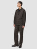 Ein Mann, der ein dunkelbraunes Overshirt von Atelier trägt, dazu eine passende Hose und darunter ein schwarzes T-Shirt.