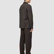 Eine Person, von der Seite gesehen, die ein dunkelbraunes Atelier Overshirt aus gebrochenem Twill und eine dazu passende Hose trägt.