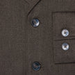 Nahaufnahme des dunkelbraunen Atelier-Overshirts aus gebrochenem Twill mit zwei Knöpfen vorne und zwei passenden Knöpfen an den Ärmelbündchen.
