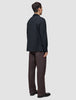 Eine Person, von hinten gesehen, die ein Atelier Overshirt Dark Navy, eine Atelier-Hose und schwarze Schuhe trägt.