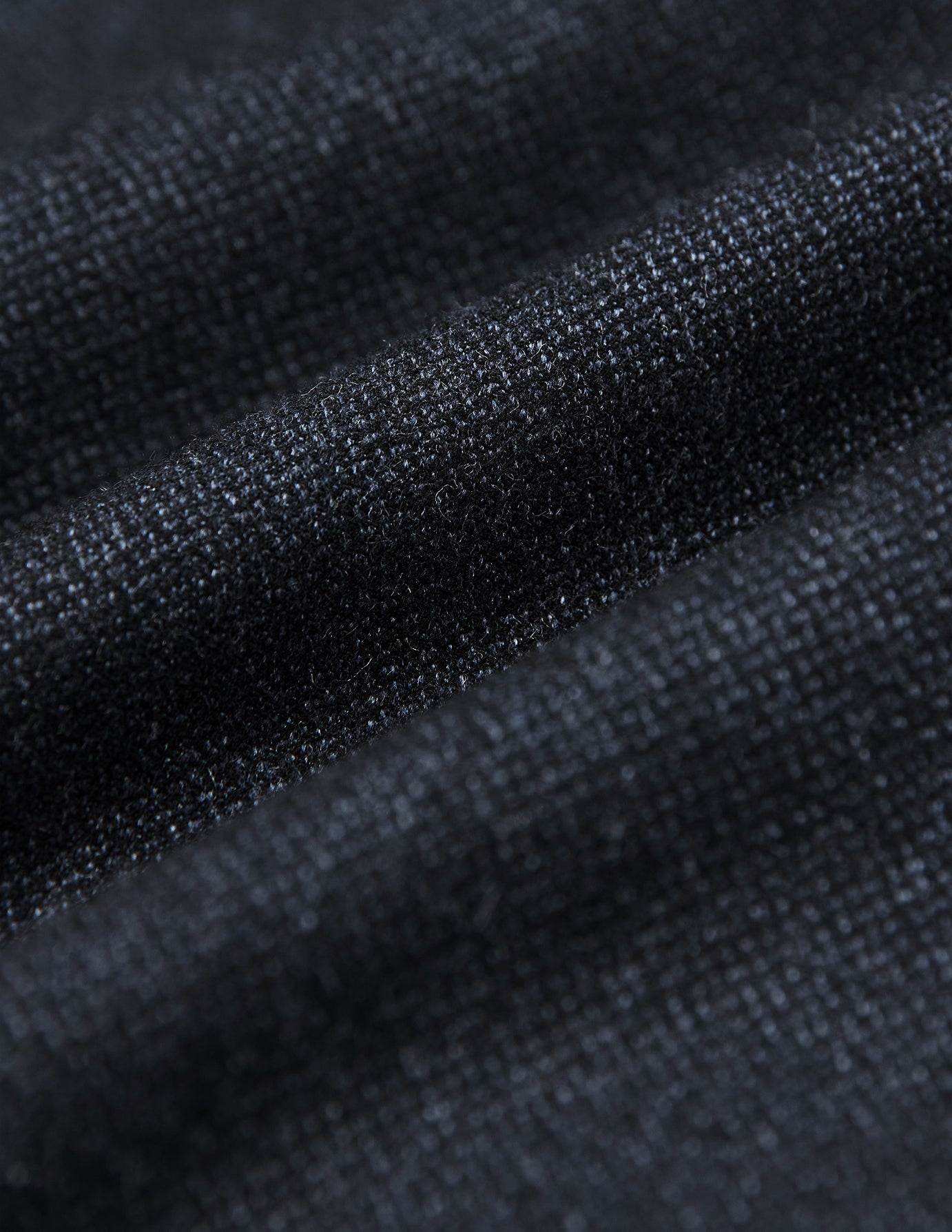 Nahaufnahme des dunkelblauen Stoffes des Atelier Overshirt, die eine strukturierte, gewebte Oberfläche zeigt, die sich zu sanften Rillen faltet.