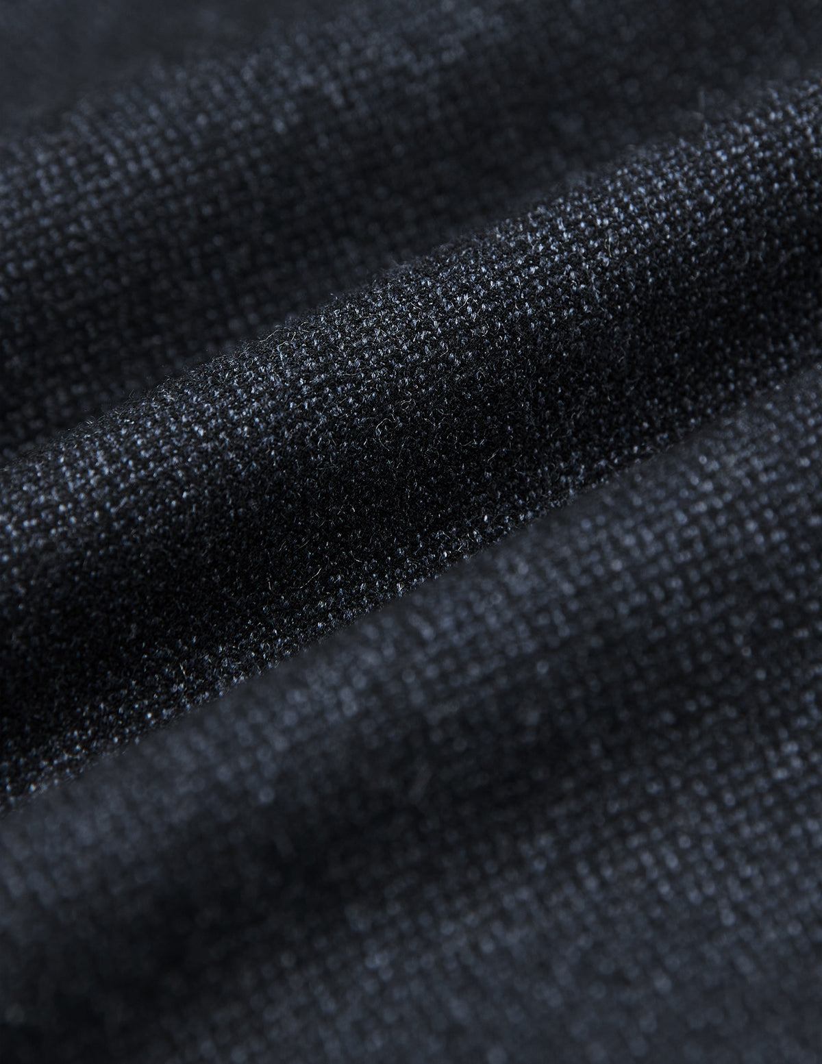 Nahaufnahme des dunkelblauen Stoffes des Atelier Overshirt, die eine strukturierte, gewebte Oberfläche zeigt, die sich zu sanften Rillen faltet.
